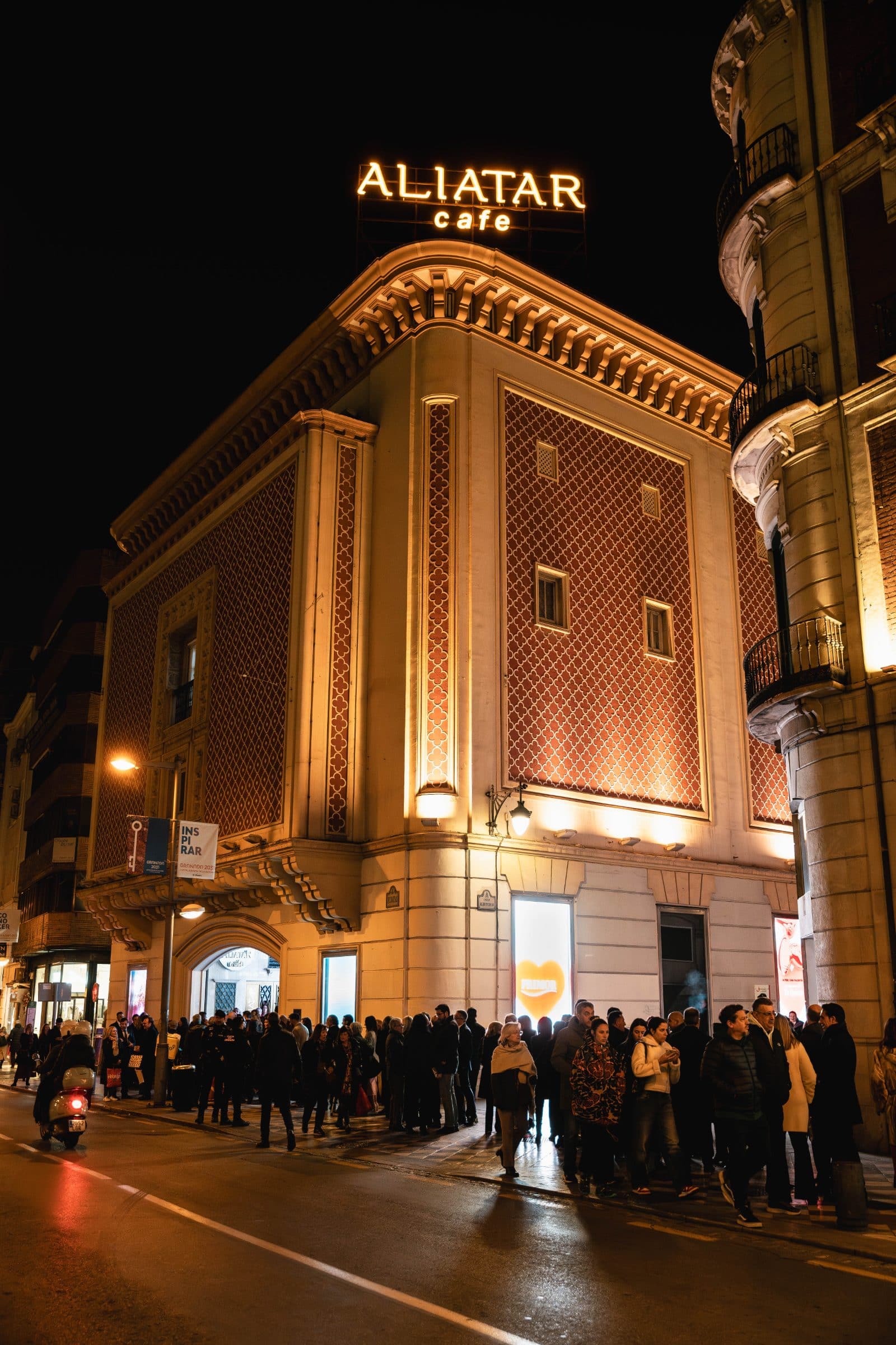 Fachada de Aliatar de noche, con el rótulo encendido y público entrando
