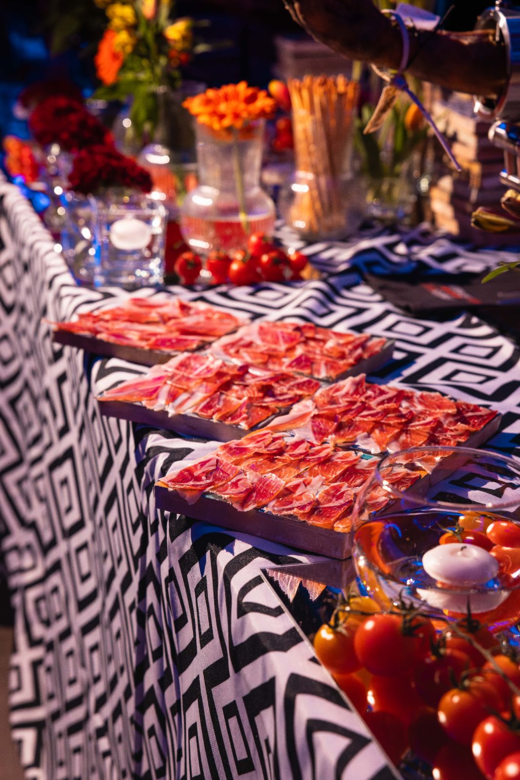 Mesa de jamón cortado con tomates y flores